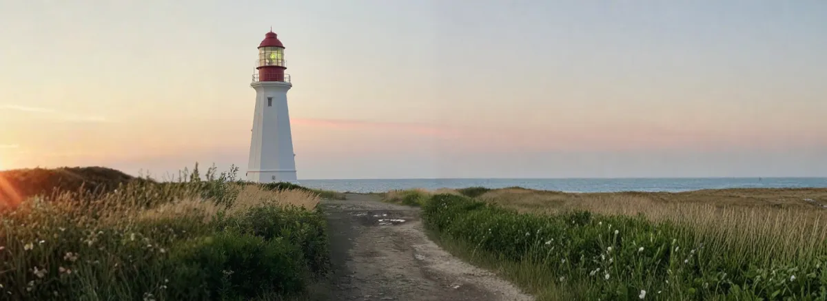 Low Point Lighthouse on Cape Breton Island looking out over the Atlantic Ocean. A rutted path leads toward the ligh the words Questions and Answers appear over the grass on the right side of the lighthouse.