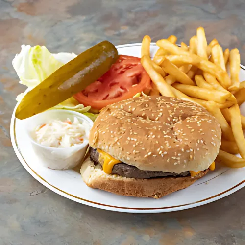 Cheeseburger Deluxe featuring a juicy beef patty, melted cheddar cheese, fresh lettuce, tomato, pickles, and onions, served on a soft sesame seed bun with crispy fries on the side