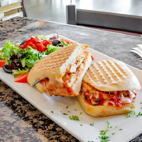 A juicy chicken burger paired with a side salad, served on a toasted bun with fresh veggies and condiments.