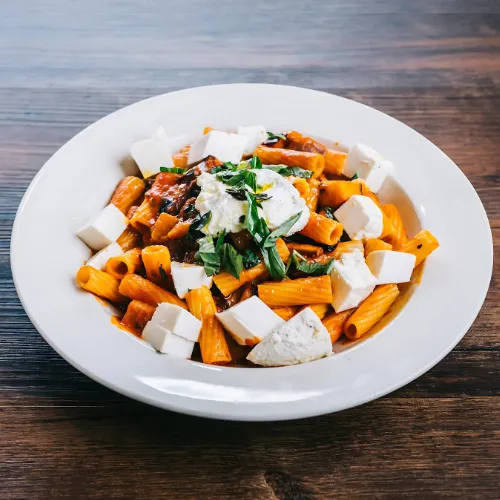  A hearty plate of rigatoni pasta topped with fresh mozzarella, grilled chicken, and spinach in a savory sauce.