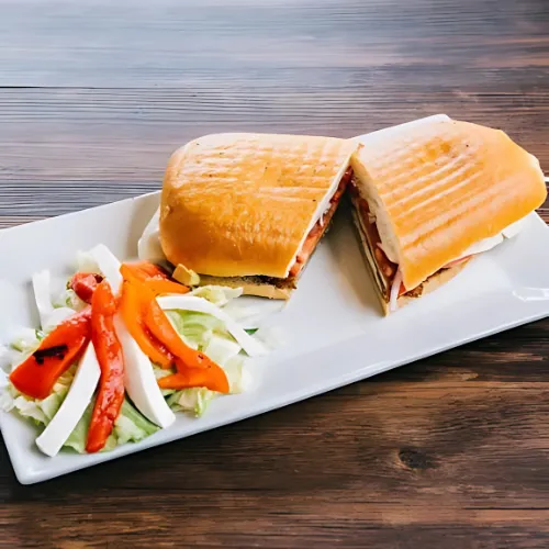 A grilled panini filled with fresh ingredients, served alongside a colorful salad of mixed greens and bell peppers.