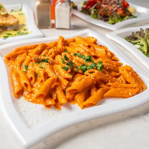  A hearty plate of rigatoni pasta topped with fresh mozzarella, grilled chicken, and spinach in a savory sauce.