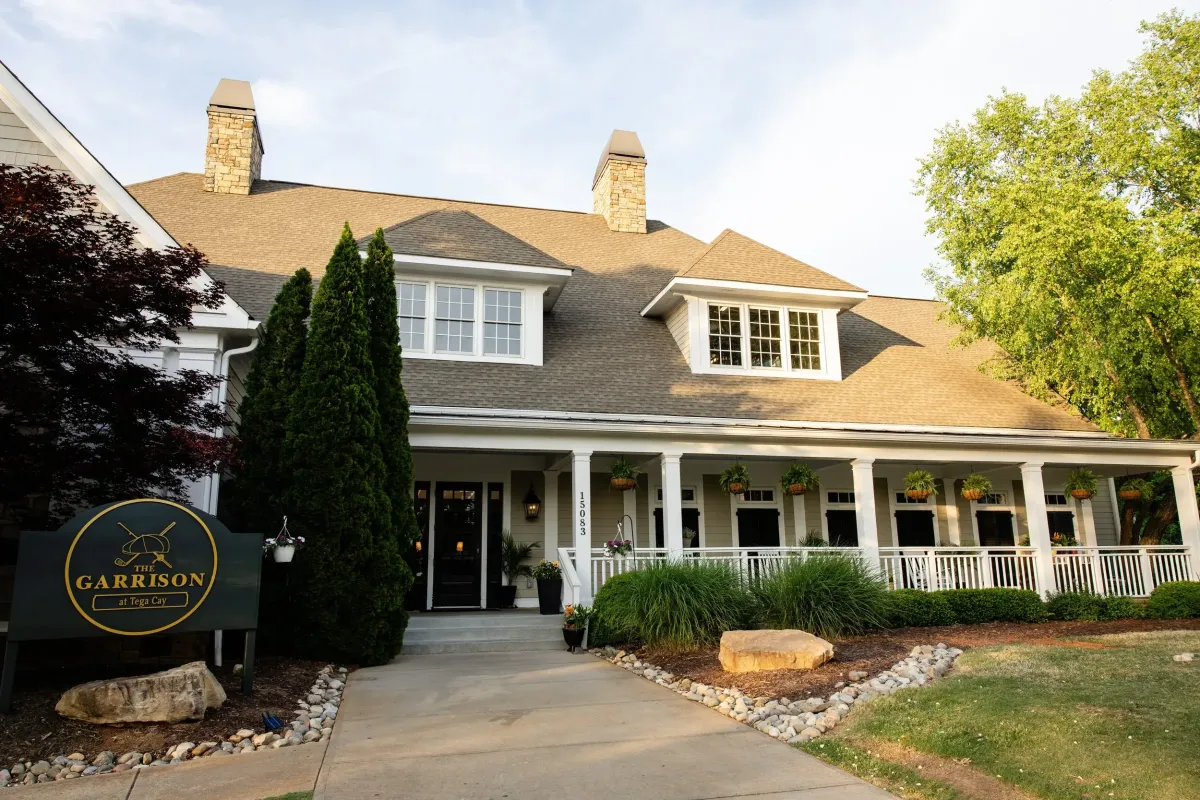 The Garrison at Tega Cay restaurant featuring a welcoming front entrance, wraparound porch, and landscaped grounds near Lake Wylie.