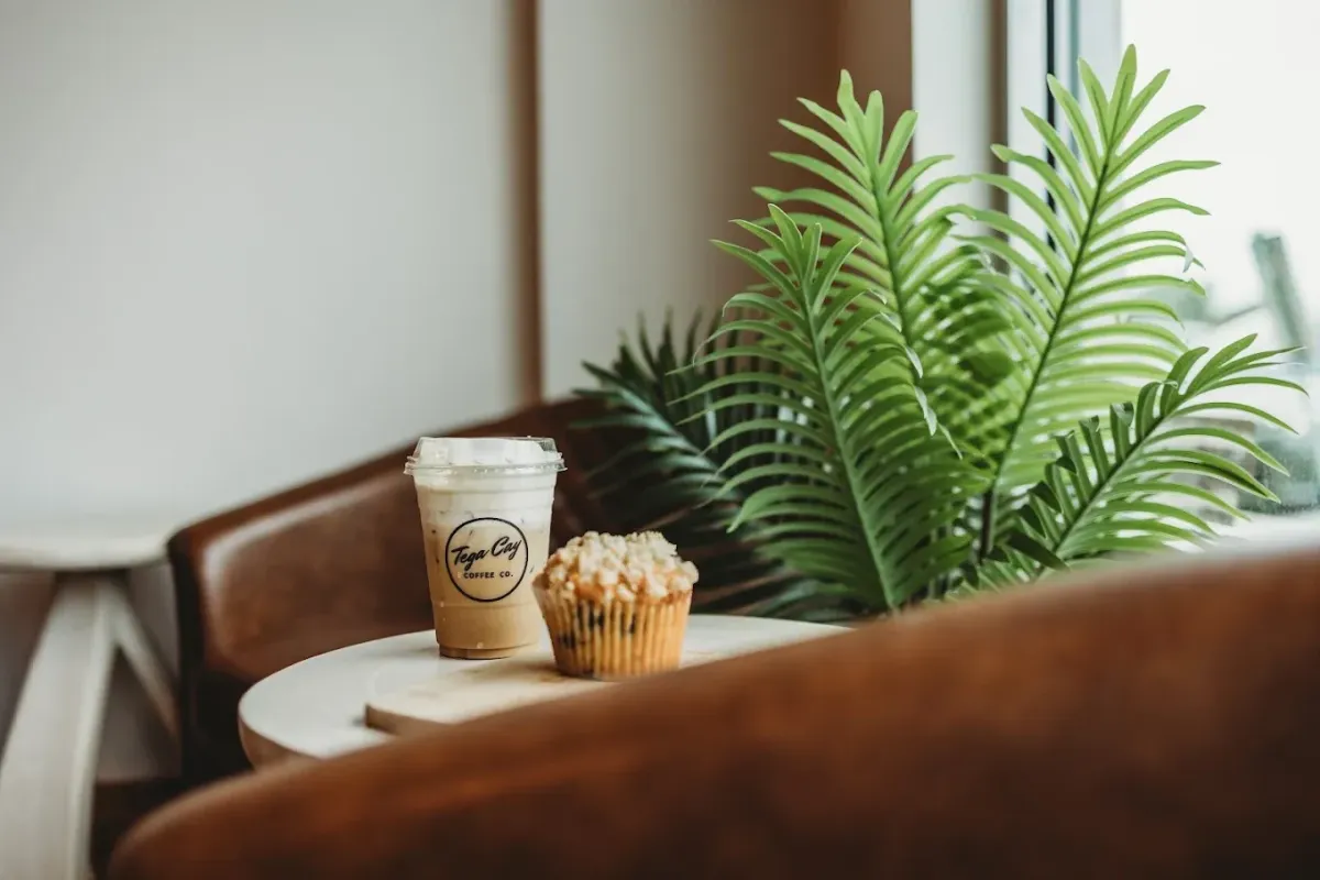 Iced coffee and fresh muffin on a table inside Tega Cay Coffee Co., a cozy neighborhood café known for locally roasted coffee and a welcoming atmosphere.