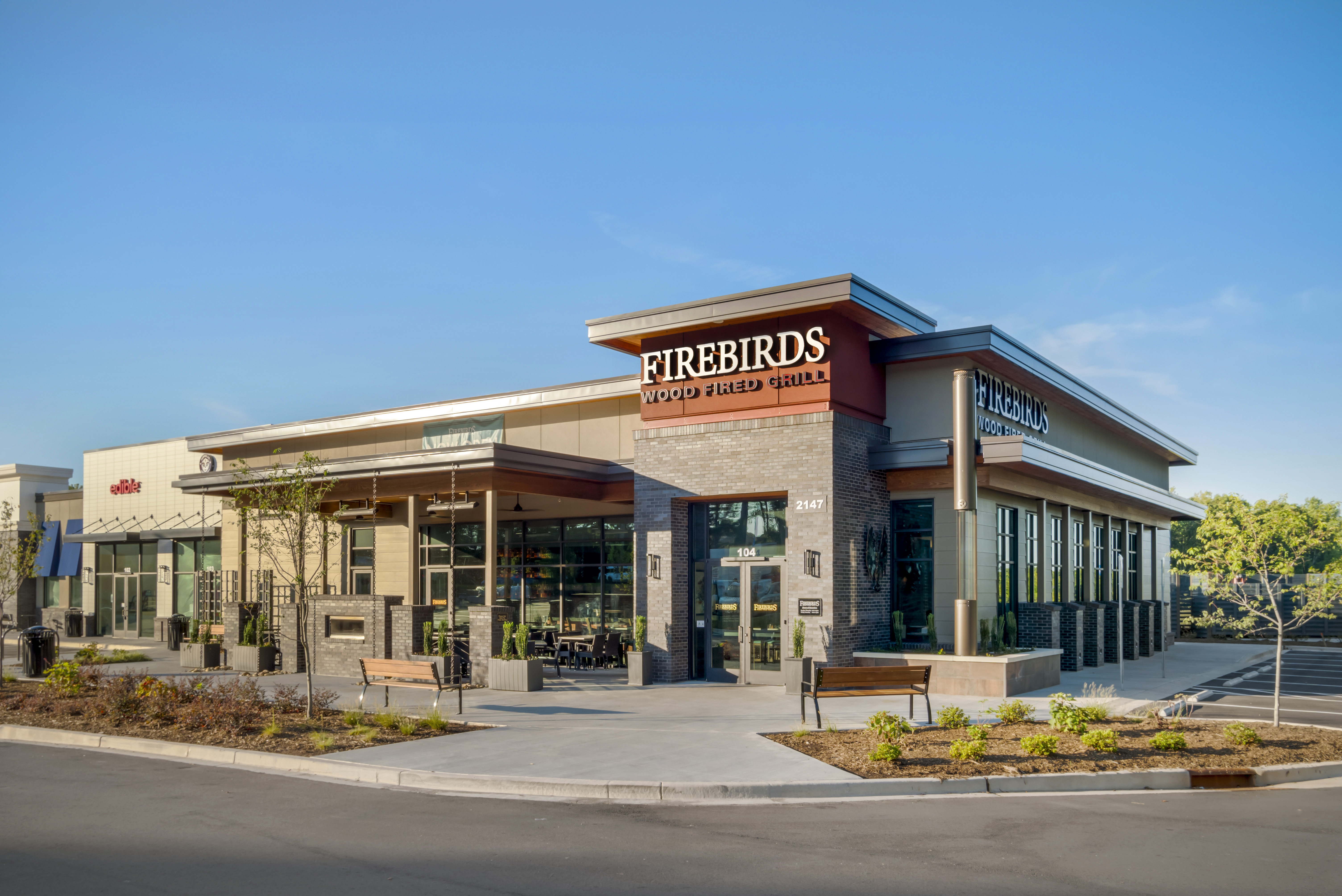Exterior of Firebirds Wood Fired Grill in Fort Mill, featuring a modern restaurant with wood-fired cuisine, outdoor patio seating, and a full-service bar.