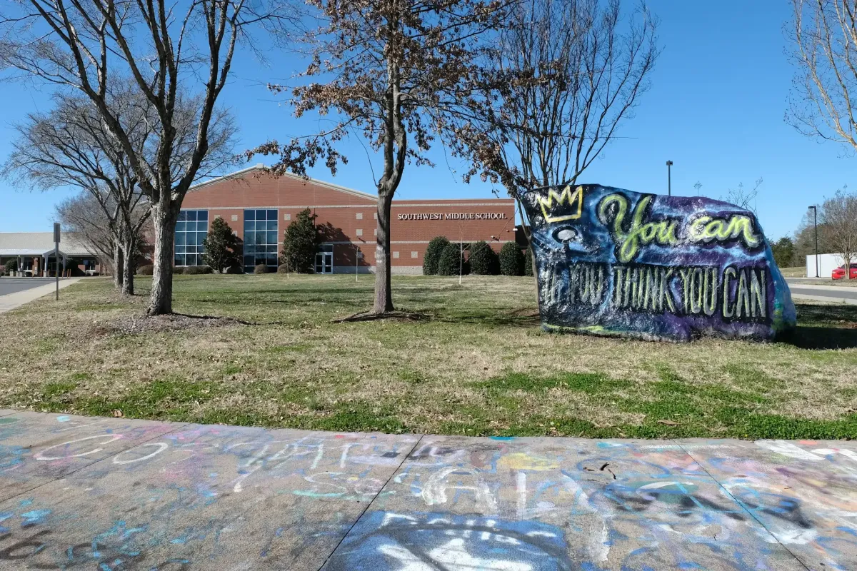 Southwest Middle School in southwest Charlotte with its brick campus building, landscaped grounds, and colorful inspirational rock at the entrance.