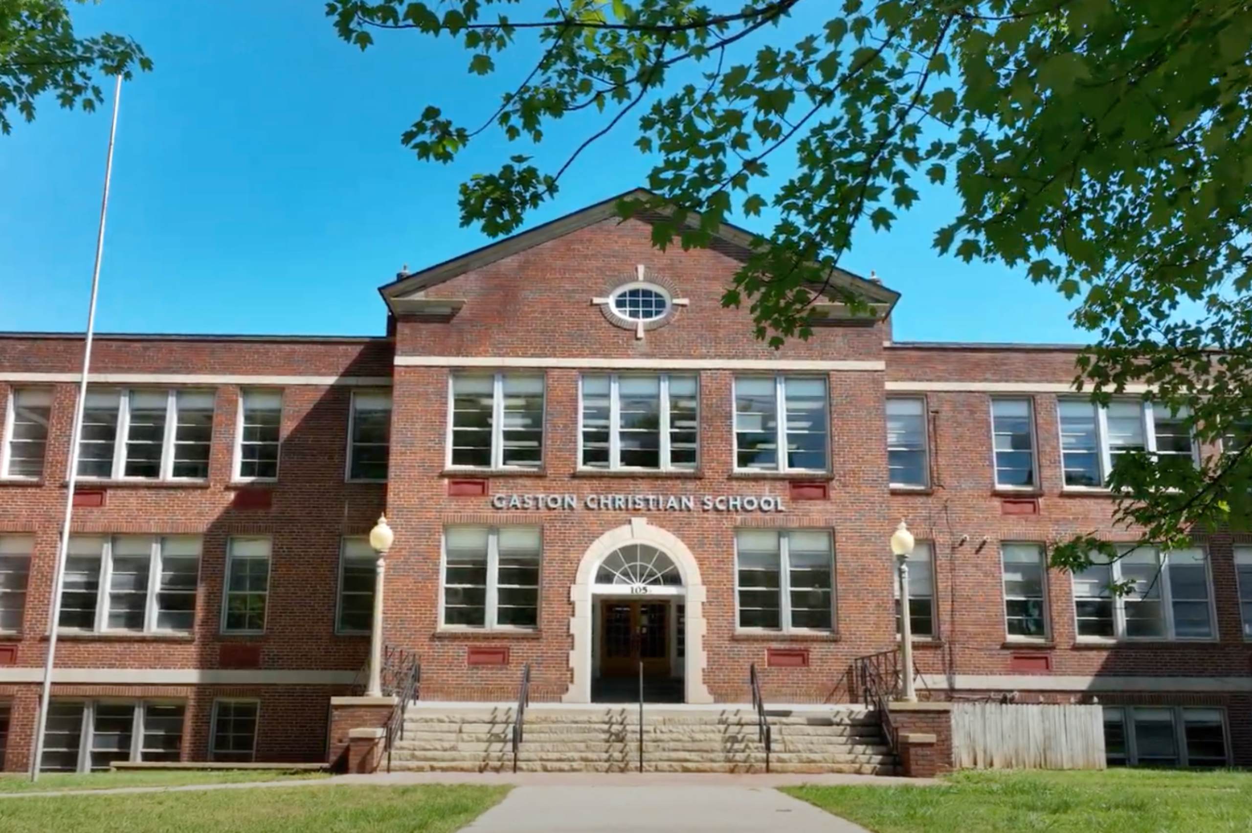 Front entrance of Gaston Christian School in Gastonia, North Carolina, featuring the historic brick campus building surrounded by trees and landscaped grounds.