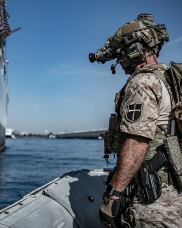 Portrait-style image of a senior instructor in a clean studio portrait: three-quarter body, confident stance, neutral backdrop, soft directional lighting emphasizing facial expression and uniform details—professional, authoritative portrait style for the academy profile.
