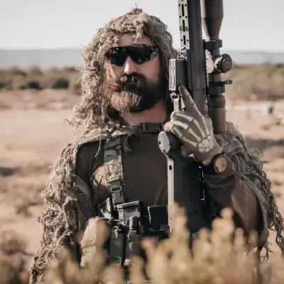 Three adult students receiving pistol fundamentals on a sunlit outdoor lane with a focused instructor demonstrating position and grip.