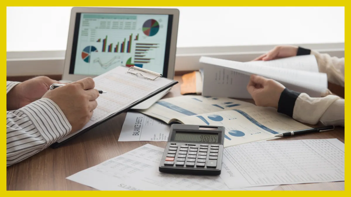 A silver pen rests on a tax document, alongside a few dollar bills and a calculator.
