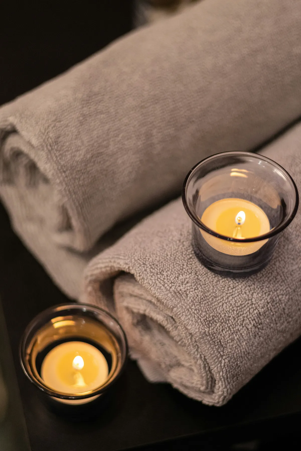 Folded spa towels beside glowing candles