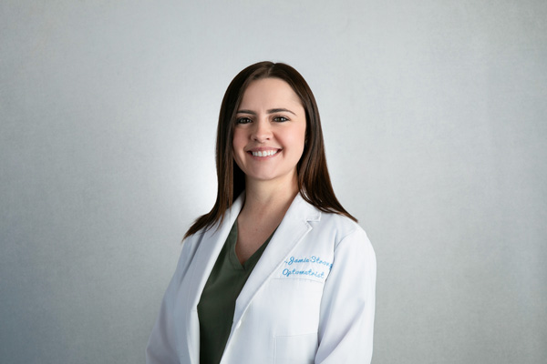 A professional woman in business attire smiles confidently against a neutral studio background. The lighting is soft and flattering, highlighting her features and creating a polished, approachable look.