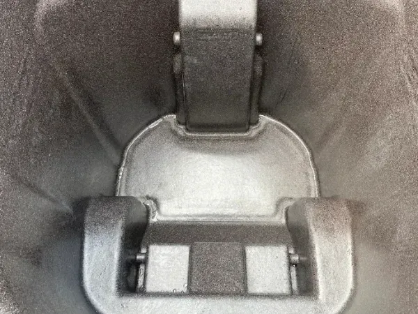 A close-up view looking down into a dark grey metal cavity with a central light grey hinge slot mechanism.