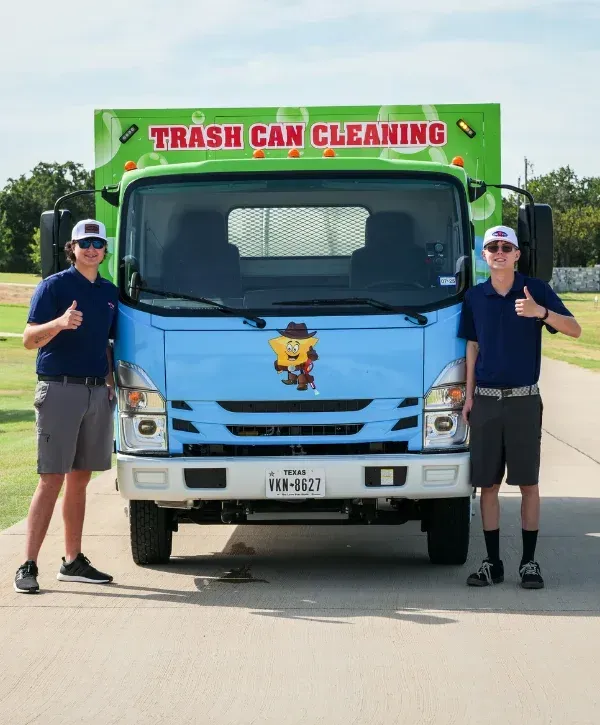 Two young men in golf attire giving thumbs up next to a light blue trash can cleaning truck with a green top.