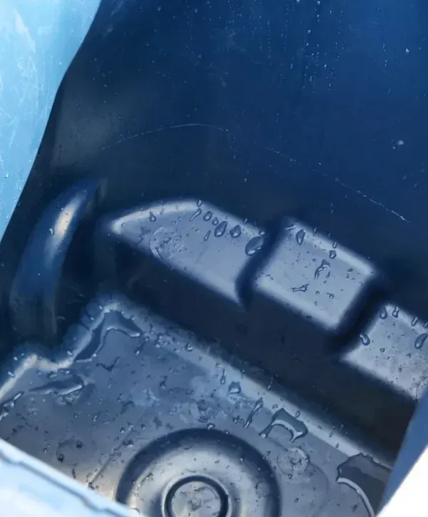 Close-up of water droplets on the dark blue molded plastic interior of a container or bin.