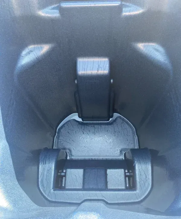 A close-up, downward view into the interior of a blue plastic garbage can with water droplets.