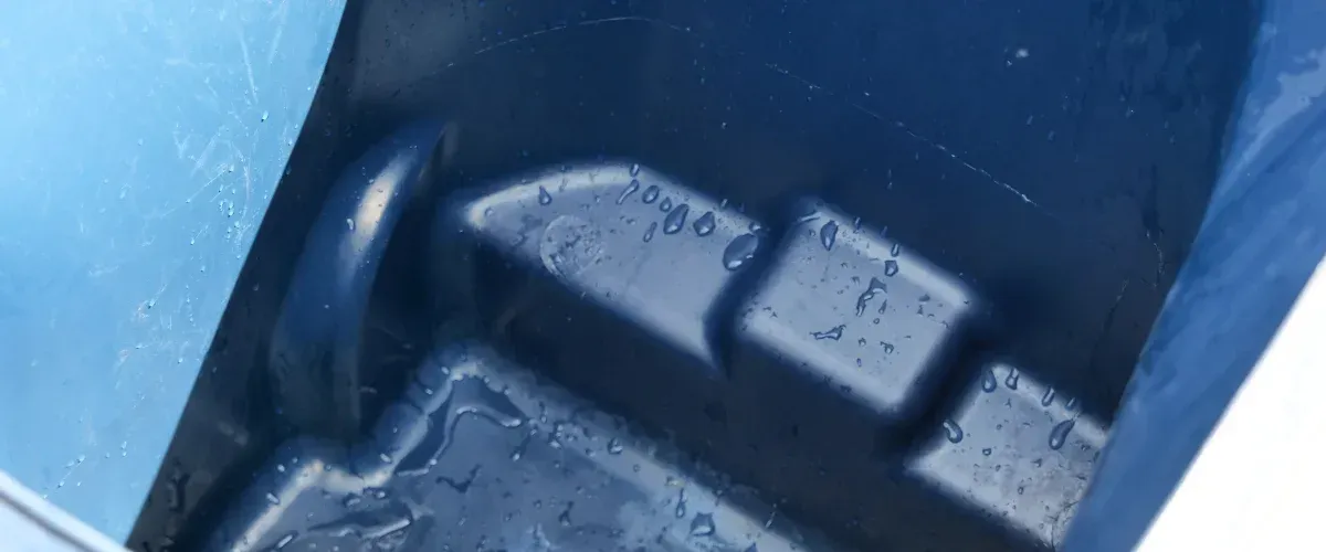 A close-up view inside a blue plastic container with water droplets clinging to its textured surface.