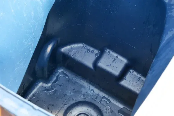 Close-up of the wet, dark blue interior of a plastic cooler or bin, showing water droplets and molded shapes.