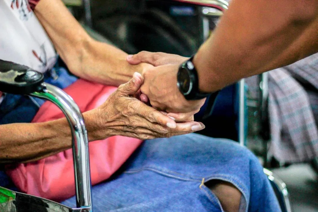 Caregiver holding hands of elderly resident — compassionate assisted living support