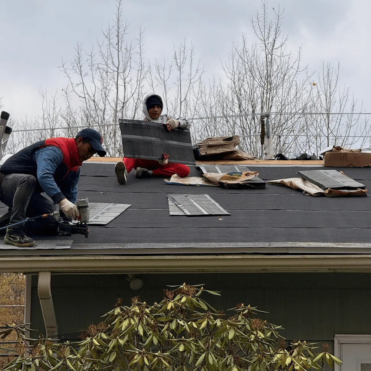 Roof repair in progress with workers replacing shingles in Massachusetts