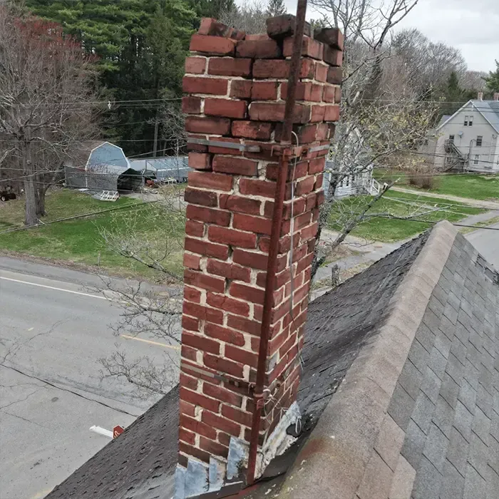 Leaning chimney structure on roof indicating potential safety risk in Boston home