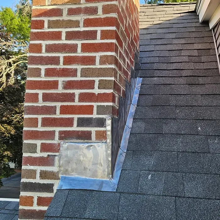 Brick chimney with step flashing installed to prevent roof leaks