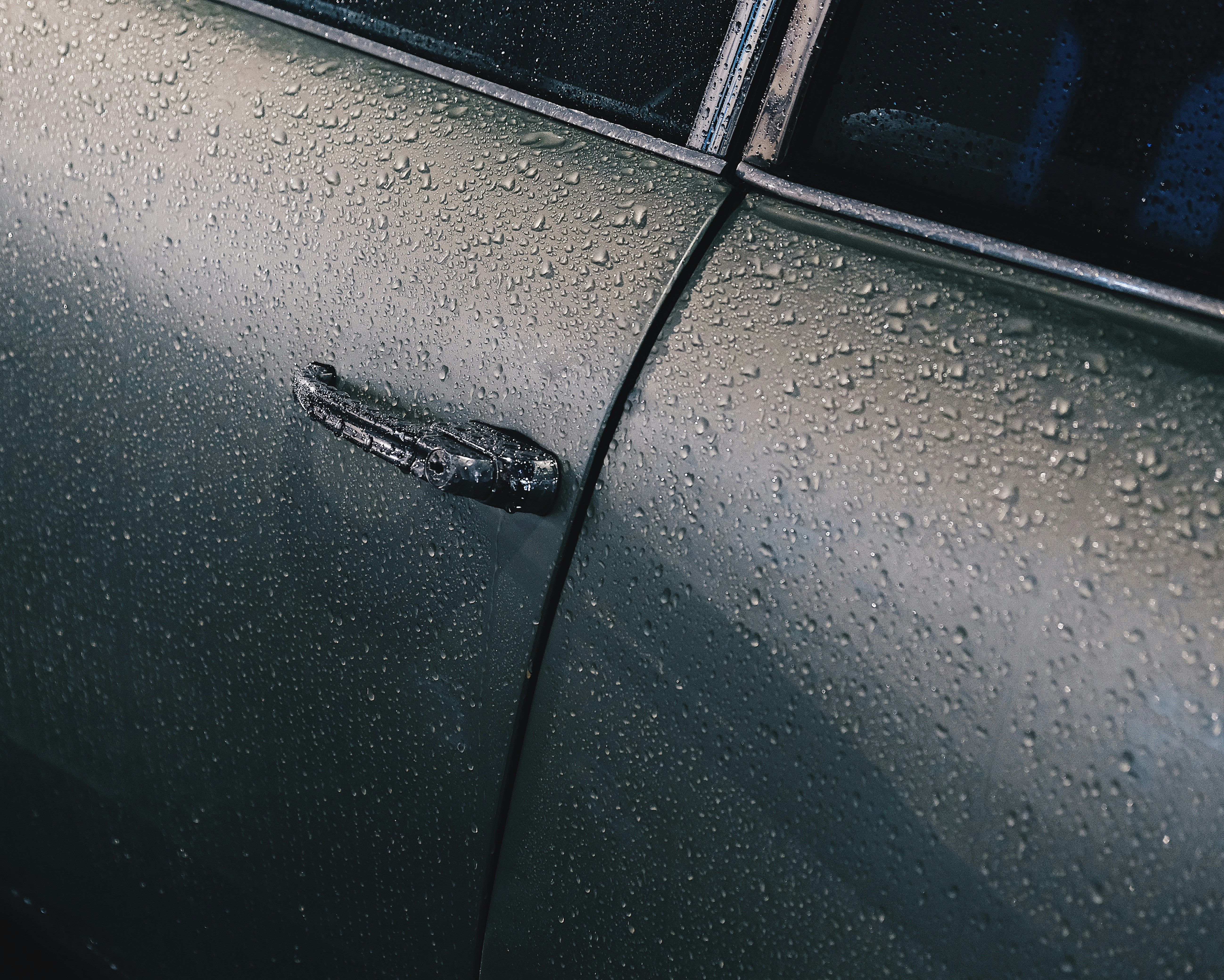 Erklärung zu Autowachs mit einer Nahaufnahme von Wasserperlen auf grünem Autolack.