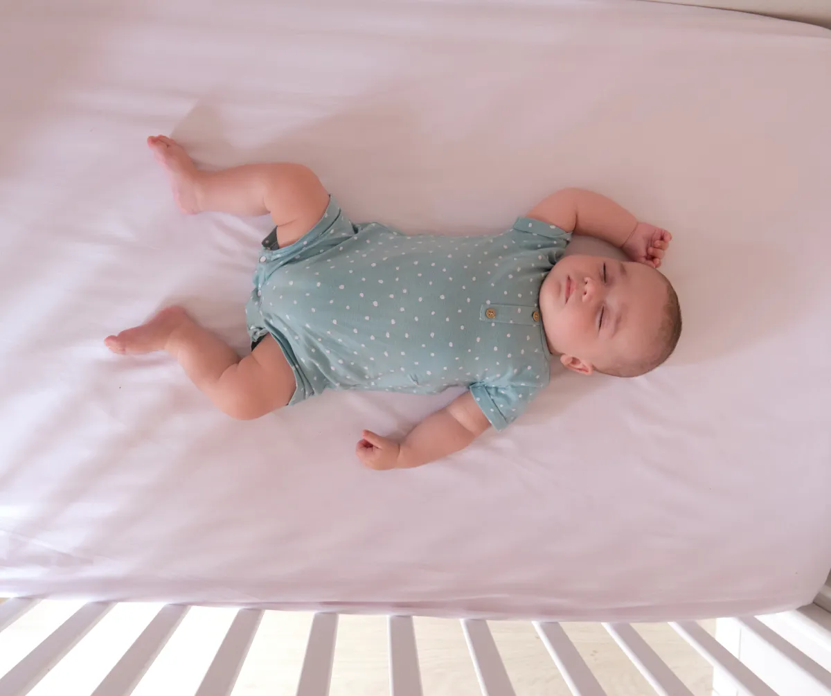 Baby lying awake in cot demonstrating undertired or overtired sleep signs