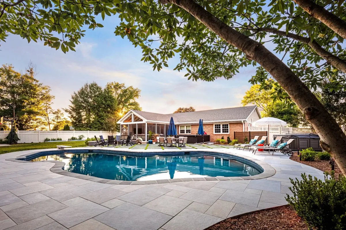 A custom swimming pool and stone patio crafted by a landscaper in Ambler, PA.