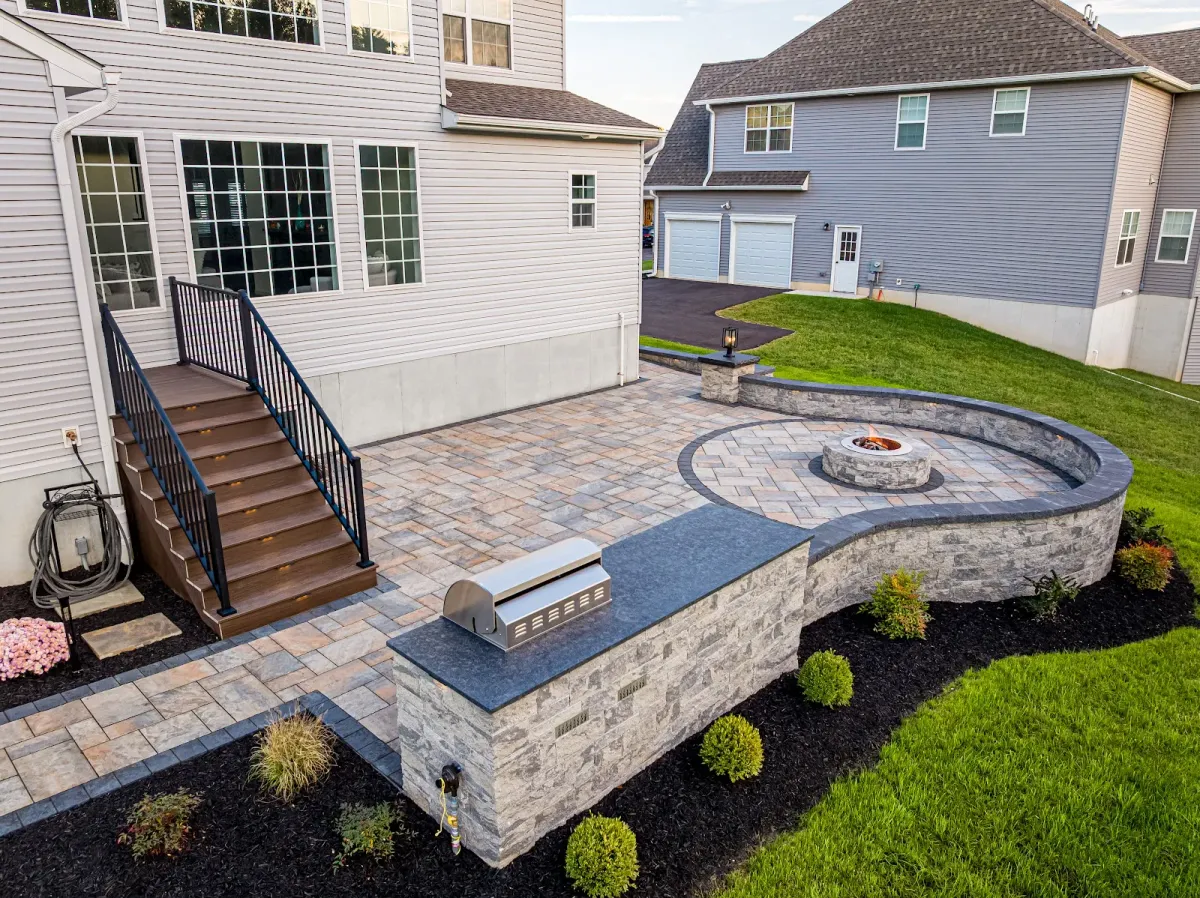 A paver patio with a fire pit and grill built by a landscaper in Bridgeport, PA.