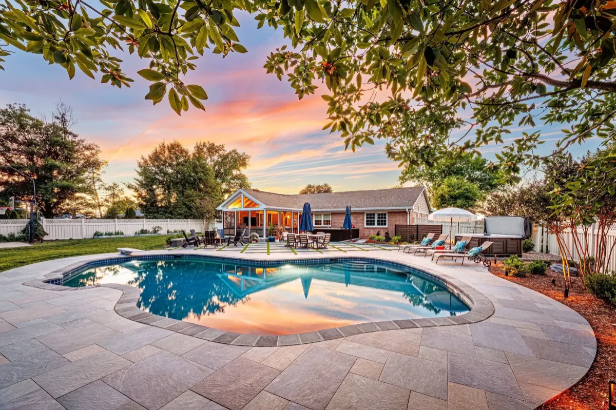 A custom stone pool patio framing a backyard oasis designed by a landscaper in Bridgeport, PA.