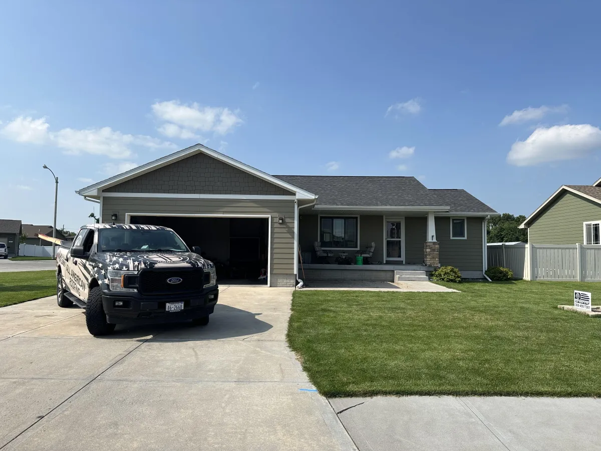 a truck in front of a house with shingle roof