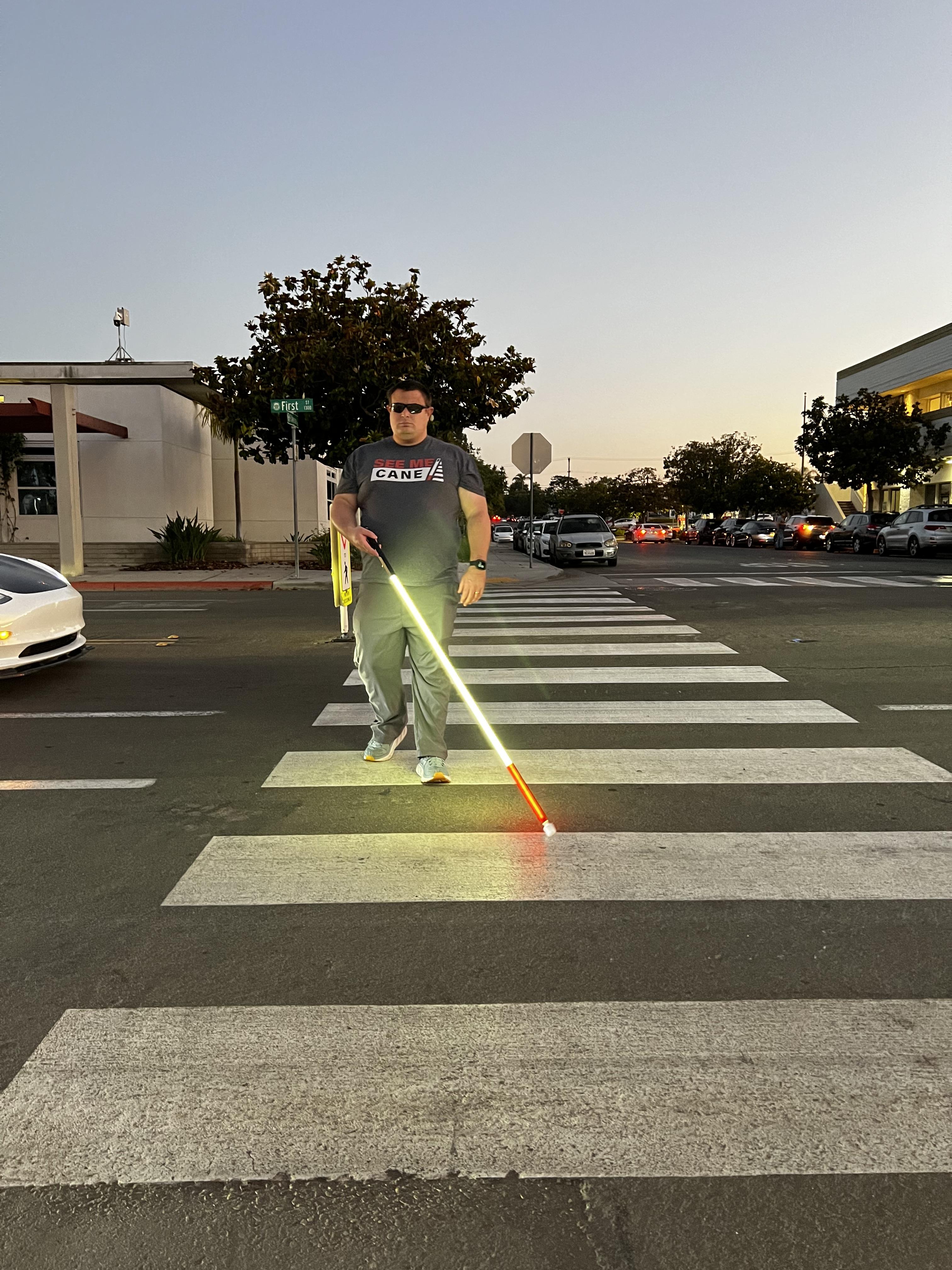 Glowing lighted white cane illuminating the pavement at sunset in a crosswalk
