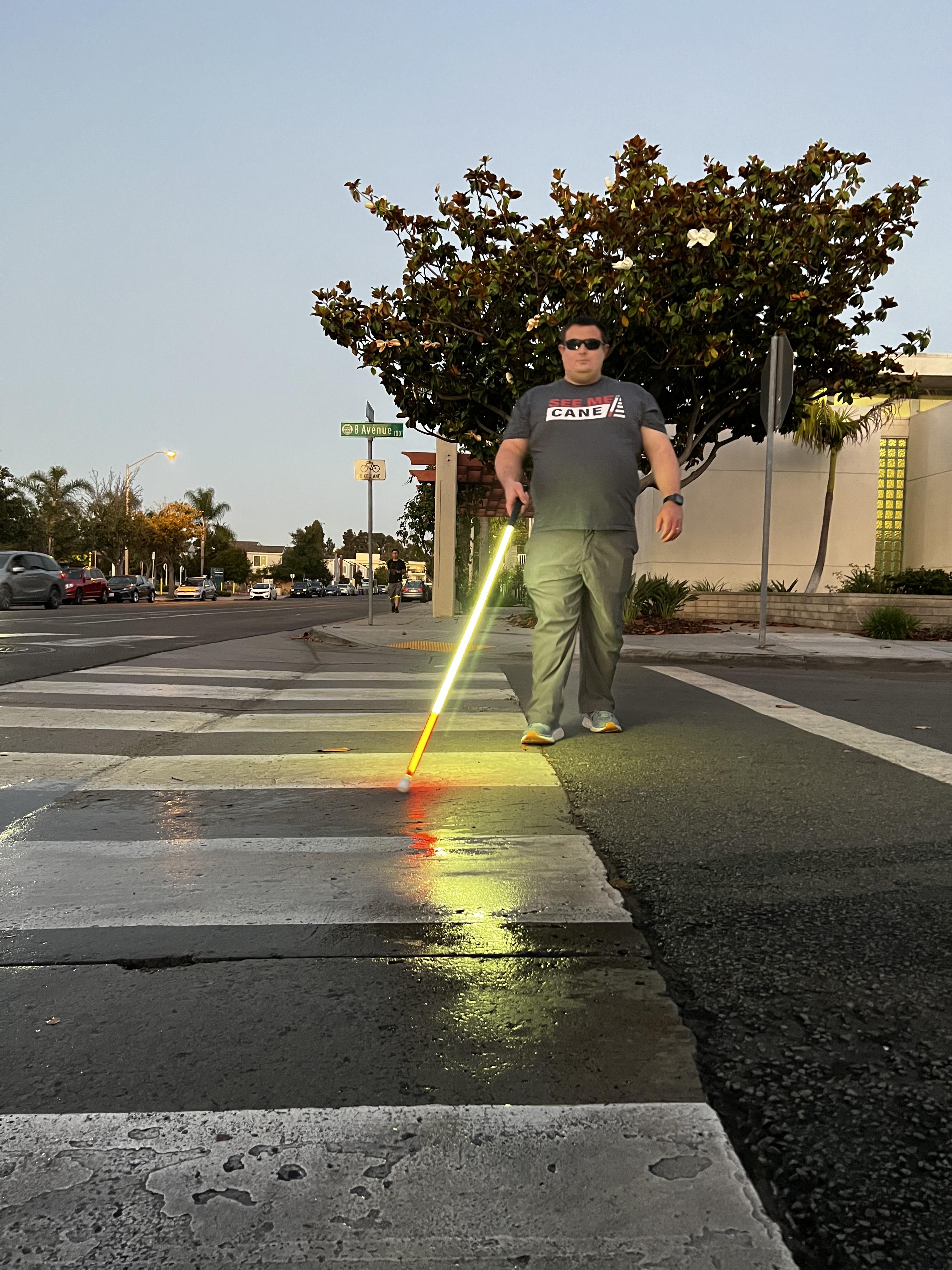 DeafBlind inventor using a lighted white cane in a crosswalk
