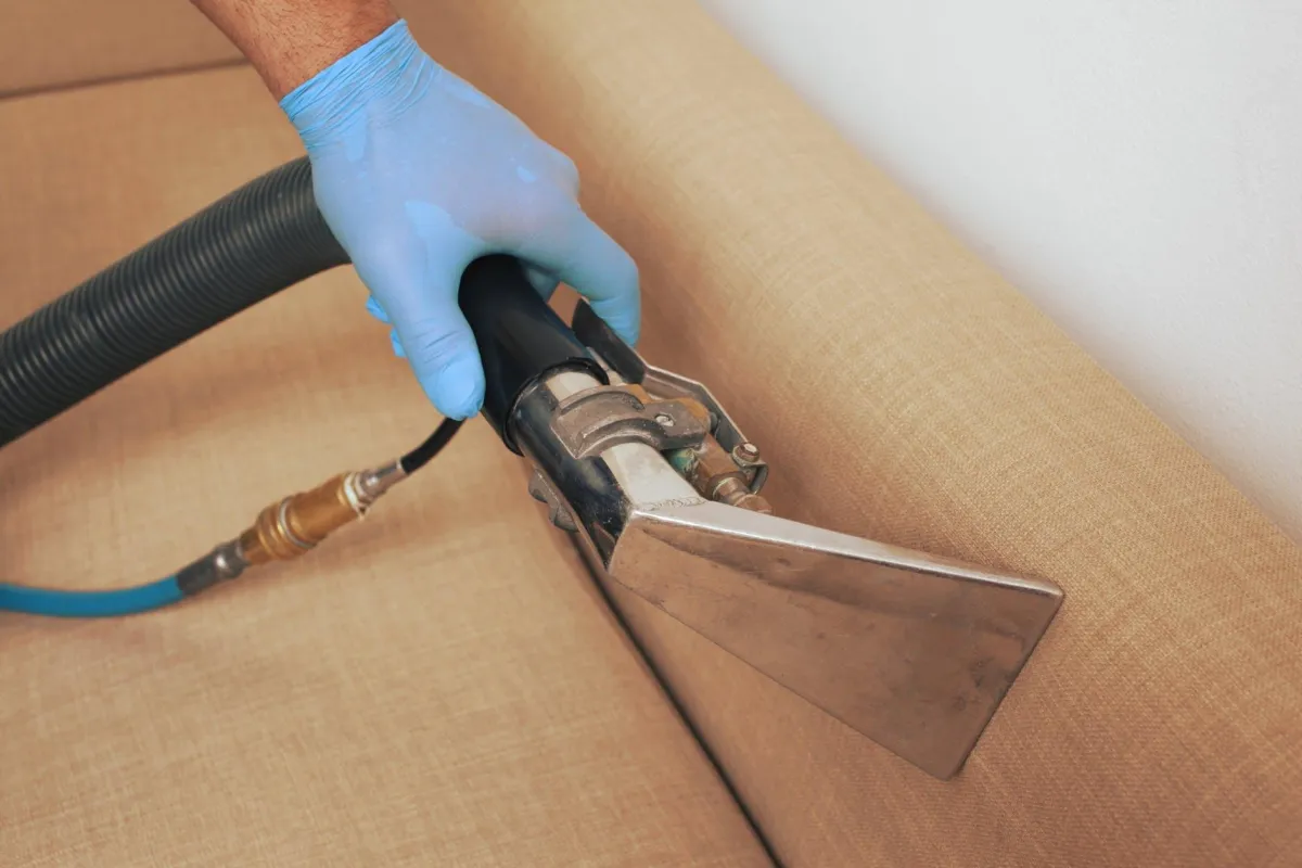 Image of a Sofa being cleaning using a hand vacuum