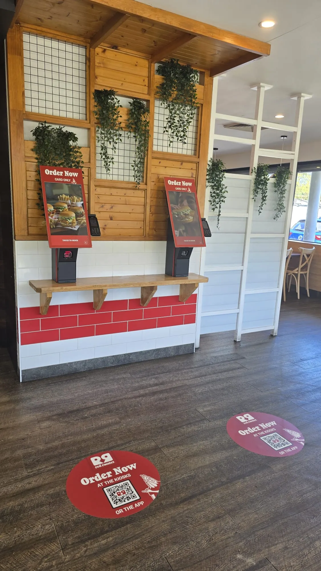 Red Rooster ordering kiosks with circular floor graphics and QR codes