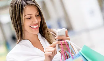 Smiling woman with shopping bags checking her phone