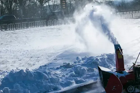 Snow blower removing deep snow buildup from commercial property