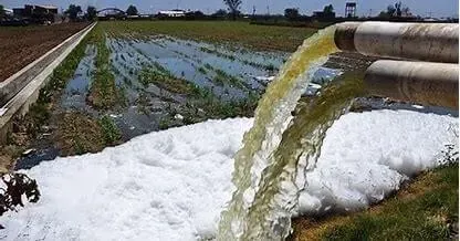 Descarga de aguas contaminadas con agroquímicos en campo agrícola de Nueva Jersey, representando los efectos invisibles de pesticidas y fertilizantes en la salud y la calidad del agua potable.