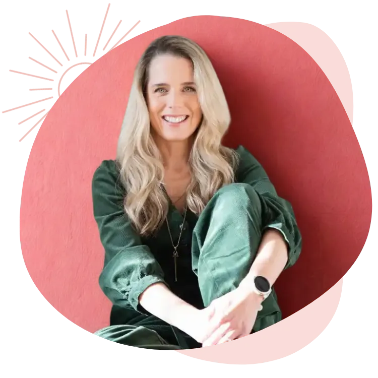 Ellie White, sober coach and women’s wellness founder, smiling while seated in a green outfit.