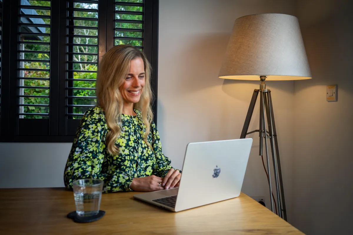Ellie White, sober coach and wellness founder, working on a laptop at home.