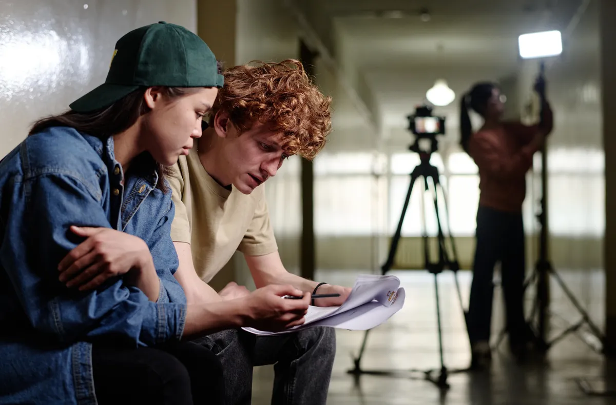 Two young individuals sitting together and reviewing script in a film production