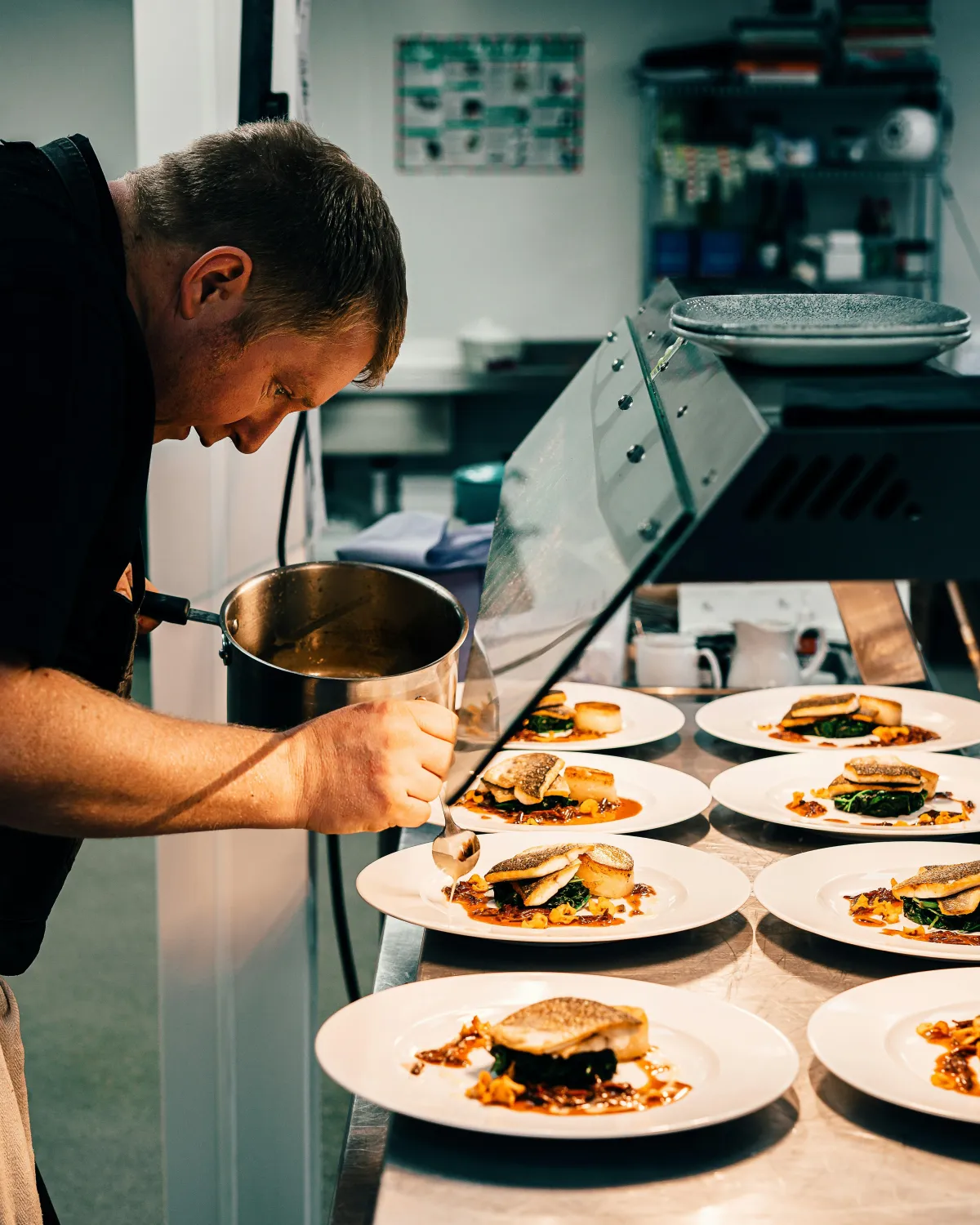 Chef carefully plating dishes in a restaurant kitchen, showcasing fine dining during Topeka Restaurant Month.