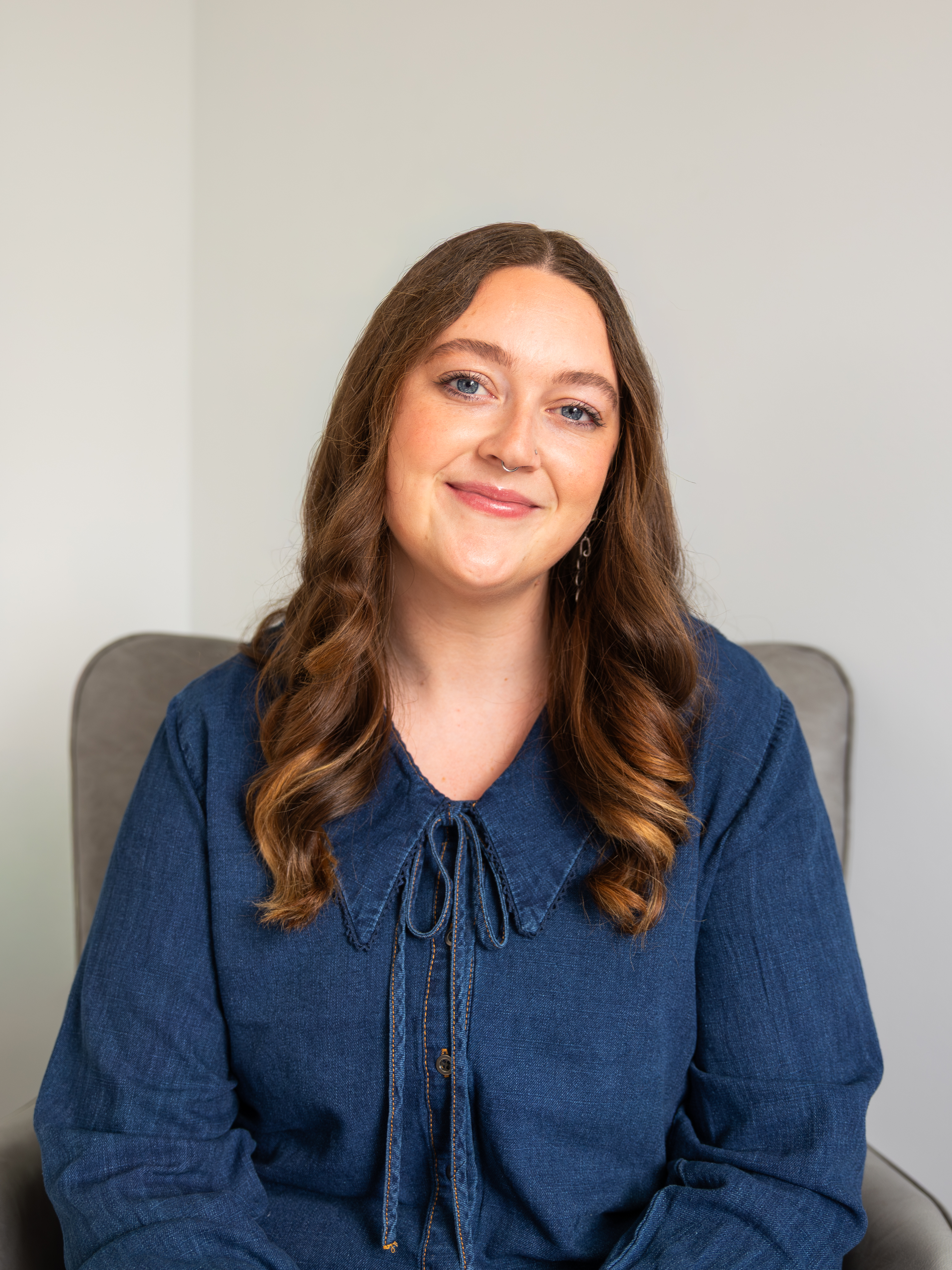 Counselor with tattoos smiling, wearing a navy blue sleeveless shirt, representing the dedicated team at Connections Counseling Center.