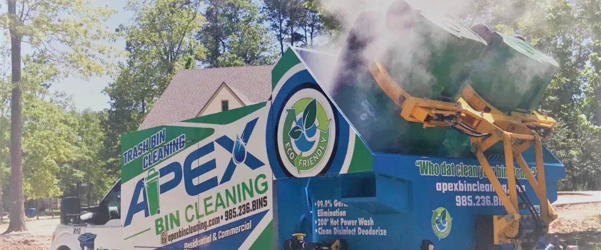 An Apex Bin Cleaning truck with green trash bins being cleaned with hot steam coming out, backed by green trees.