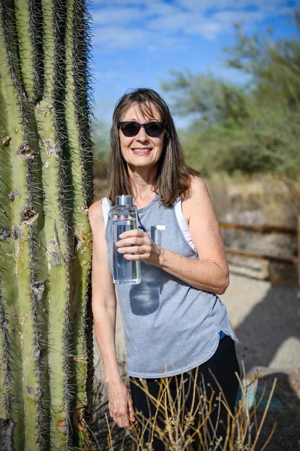 Ilene founder of Luv2Live Ilene holding clean filtered water bottle outdoors in Arizona desert — cellular health educator and autoimmune recovery advocate 11 years relapse free — luv2liveilene.com