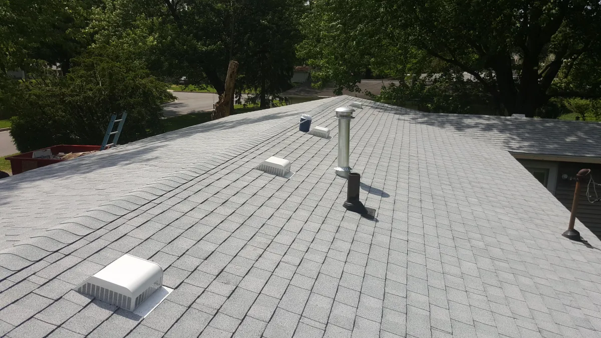 Residential roof under bright summer sunshine, demonstrating the effects of heat and the importance of proper roof ventilation.