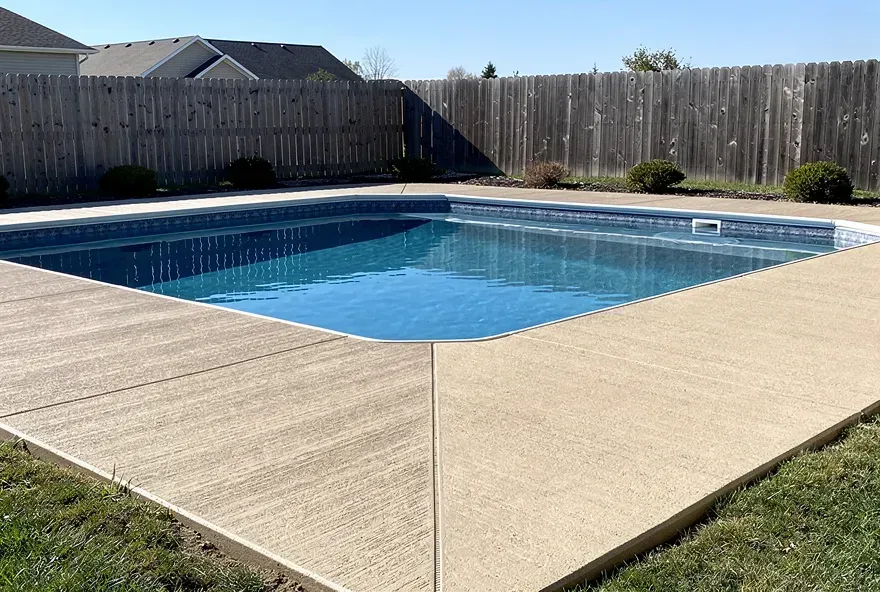 Finished textured concrete pool deck surrounding a backyard pool in Pendleton, Indiana.