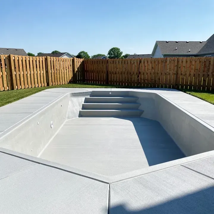 Freshly poured concrete pool deck surrounding an empty pool shell in Pendleton, Indiana.