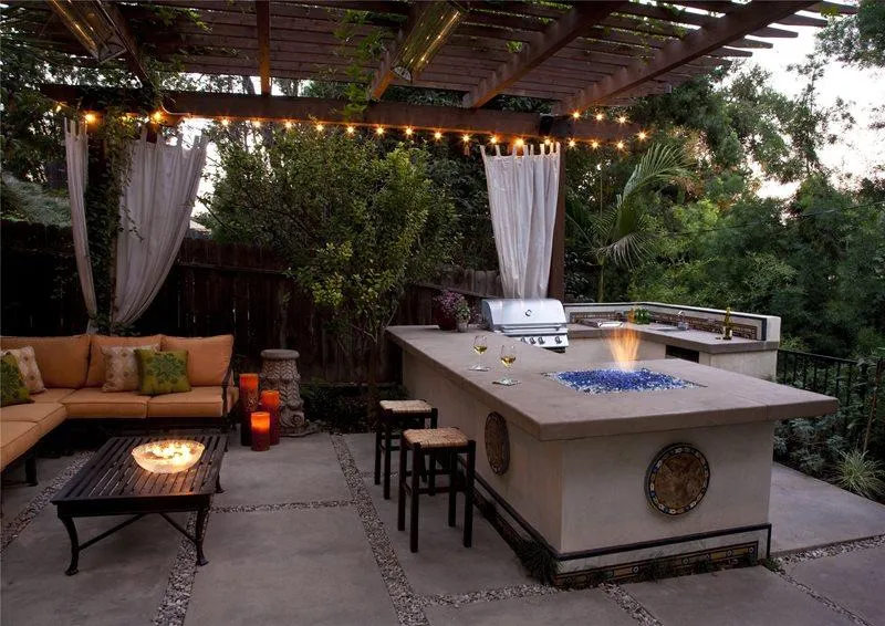 Outdoor patio with pergola, string lights, built-in grill and bar, fire feature, and seating area with sofa and table.